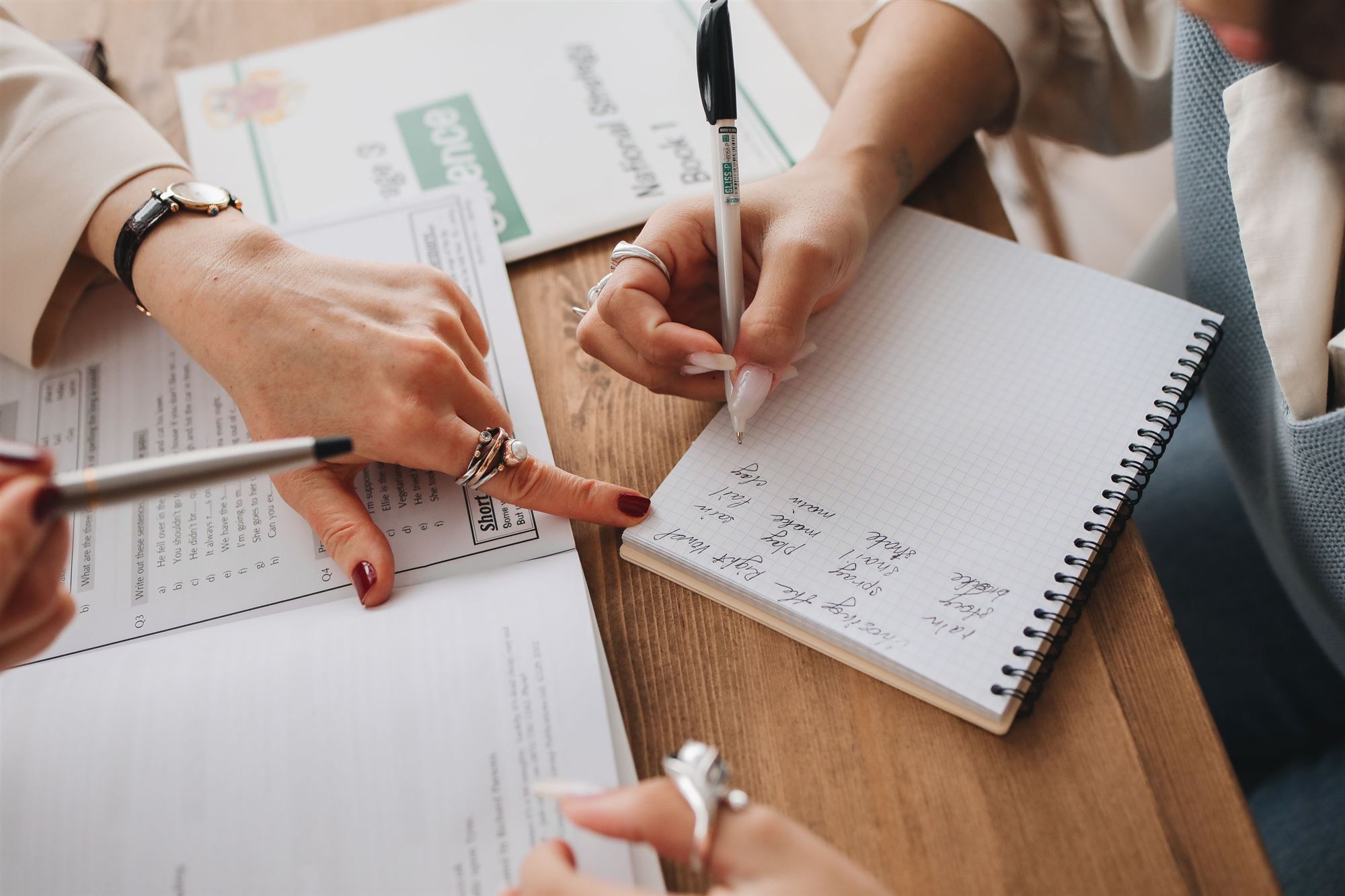 Two people working through notes together at a wooden table
